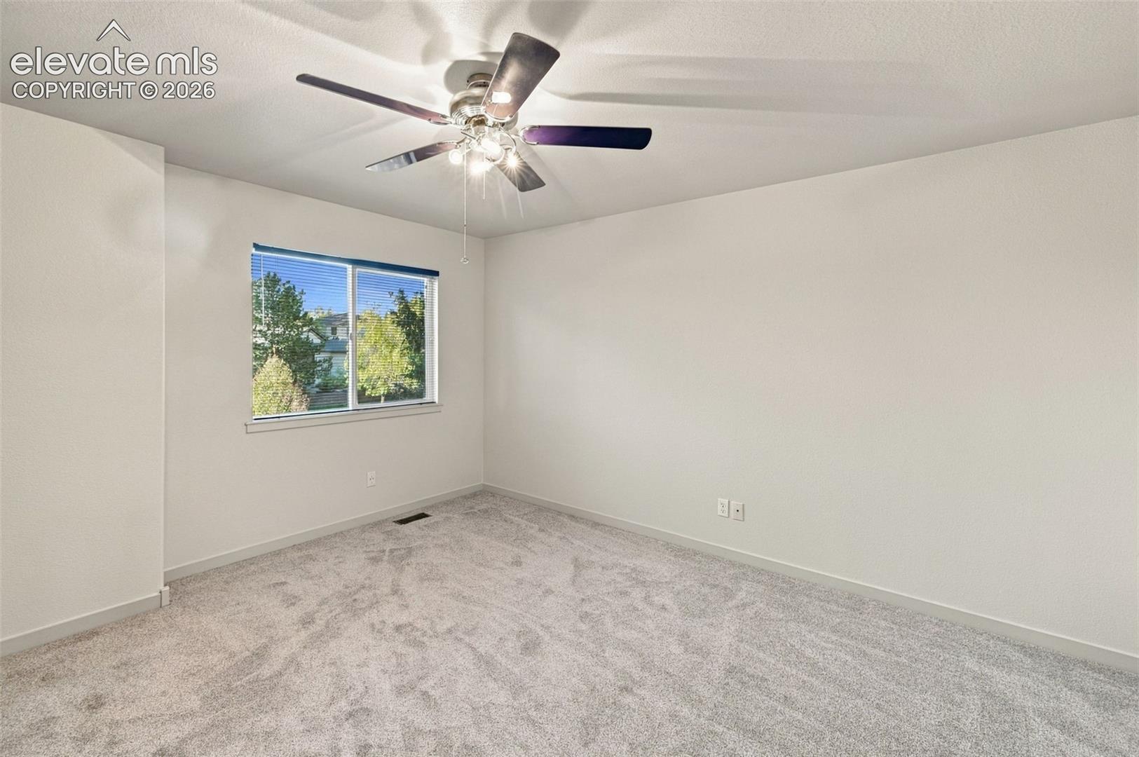 Neutral-toned carpeting, multi-blade ceiling fan with integrated lighting, and single-hung window