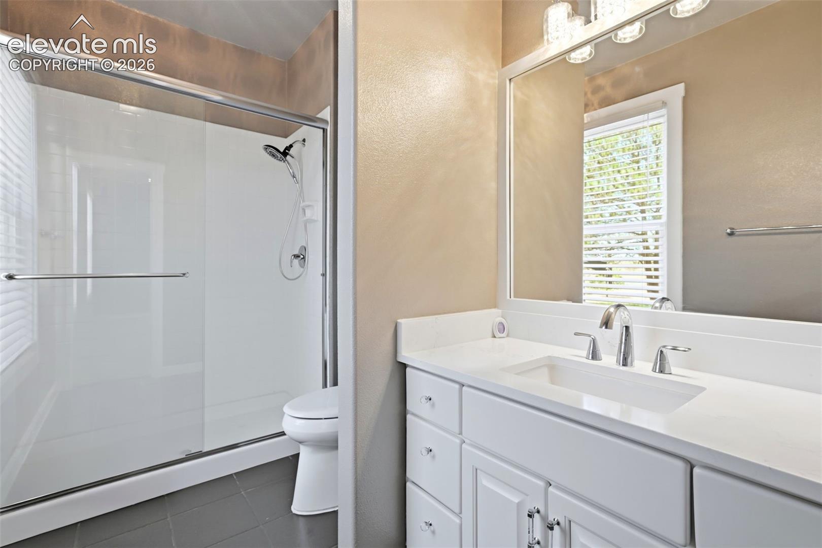 Modern bathroom featuring a white vanity with integrated sink, chrome fixtures, and a large mirror with sconce lighting