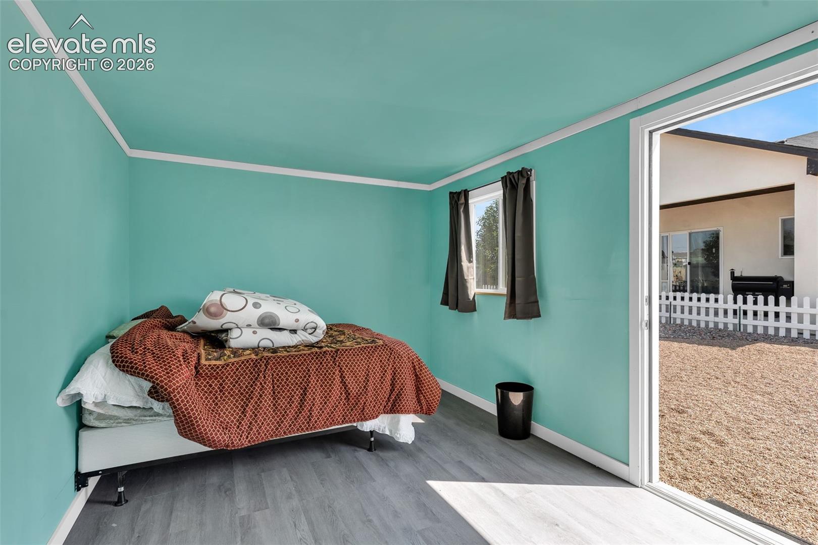 Interior space featuring wood-finish flooring, two windows with dark curtains, and white crown molding