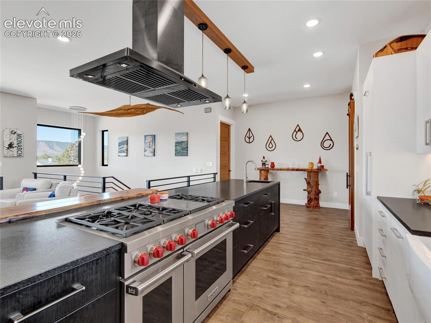 Gourmet kitchen featuring a professional-grade range, stainless steel vent hood, expansive island with dark cabinetry, and recessed lighting