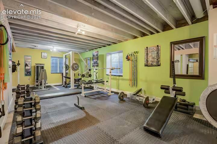 Dedicated fitness space featuring a rubber mat flooring system and exposed ceiling joists