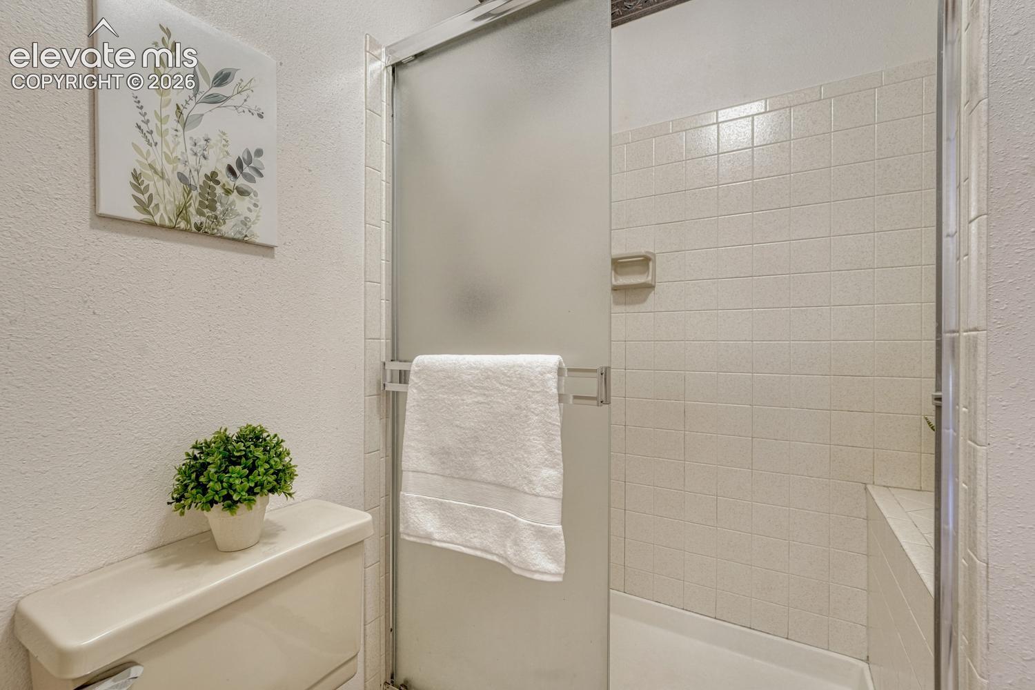 Primary bathroom with tiled shower and built-in seat.