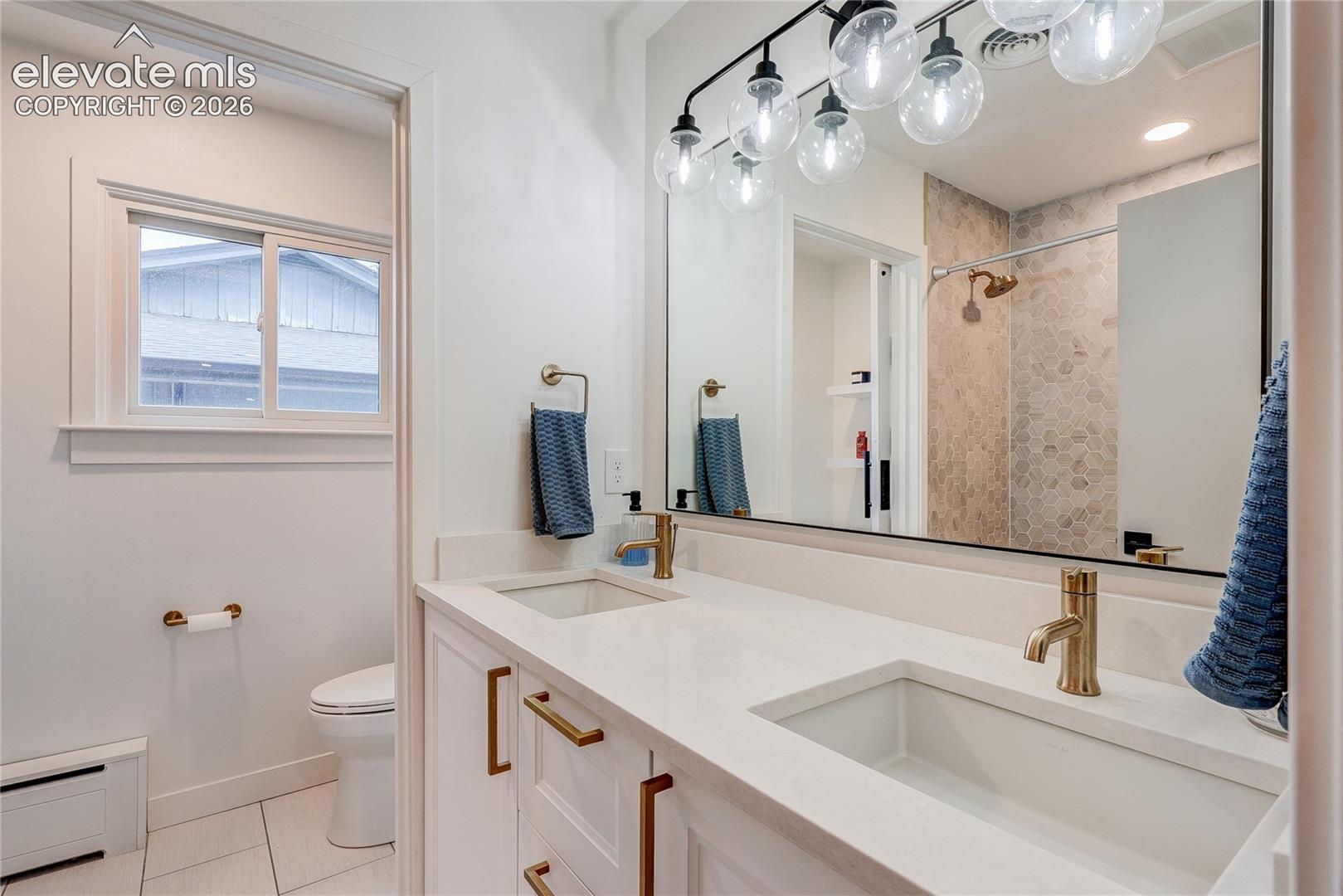 Dual vanity with integrated sinks, brass-finish fixtures, and a large wall-mounted mirror