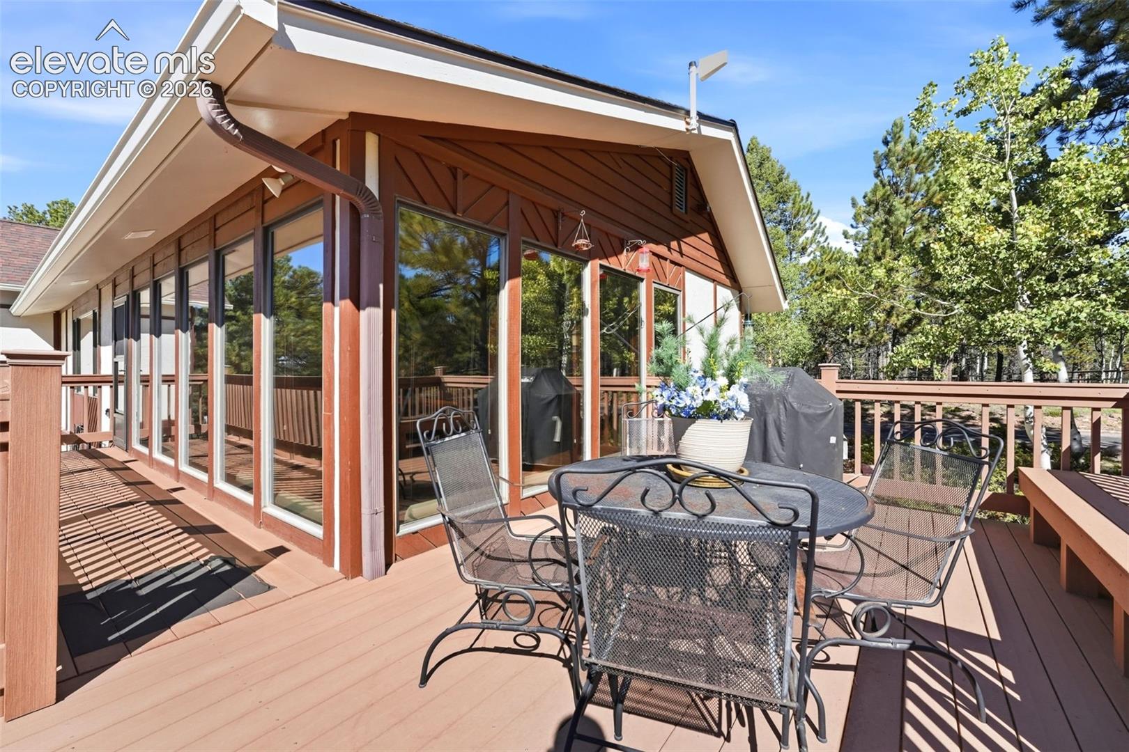 Expansive outdoor deck featuring wood-finish railing, built-in bench seating, and abundant natural light