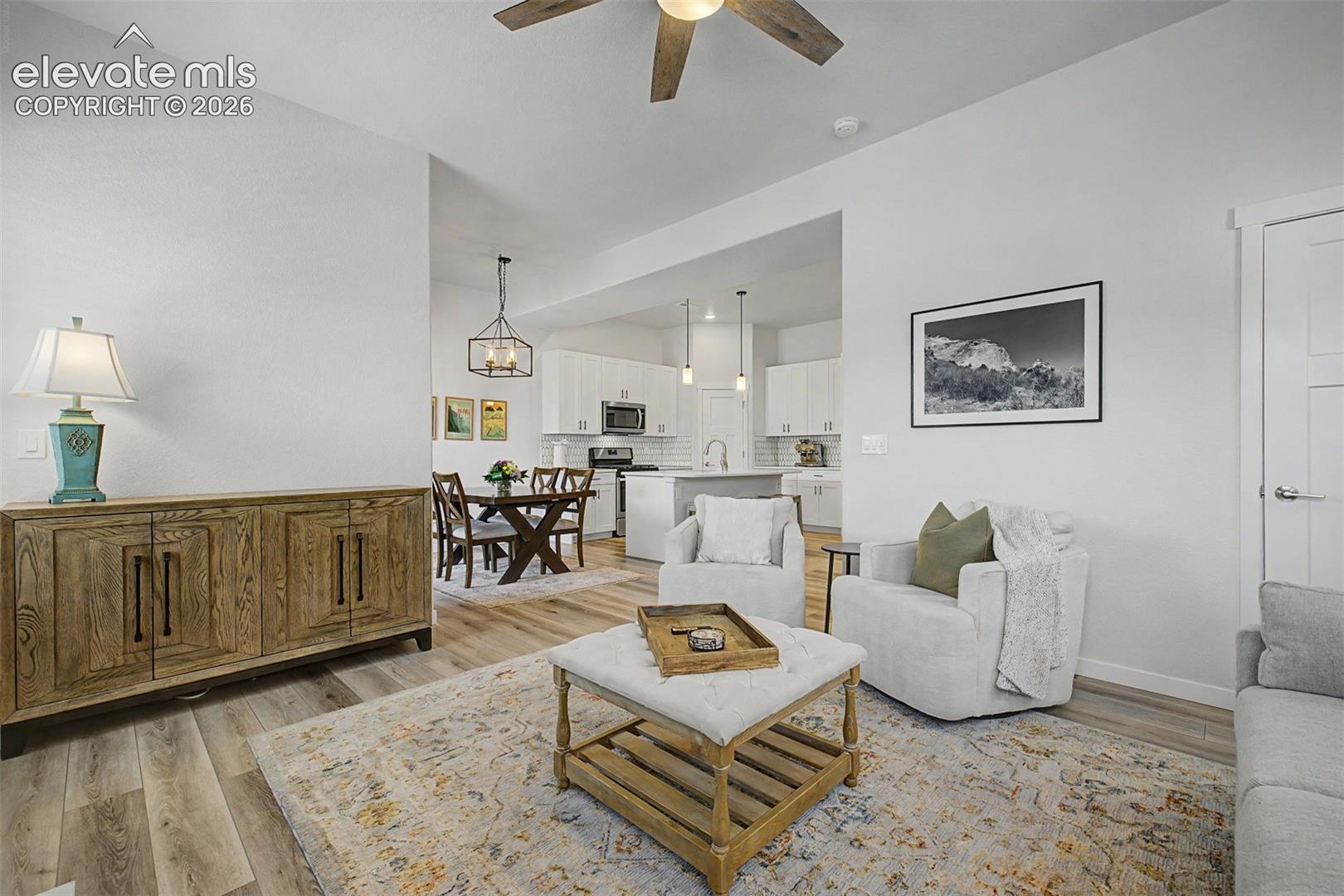 The true heart of this home comes into view — a seamlessly connected living, dining, and kitchen space where conversation flows as naturally as the light, and every corner is thoughtfully furnished without feeling overcrowded.