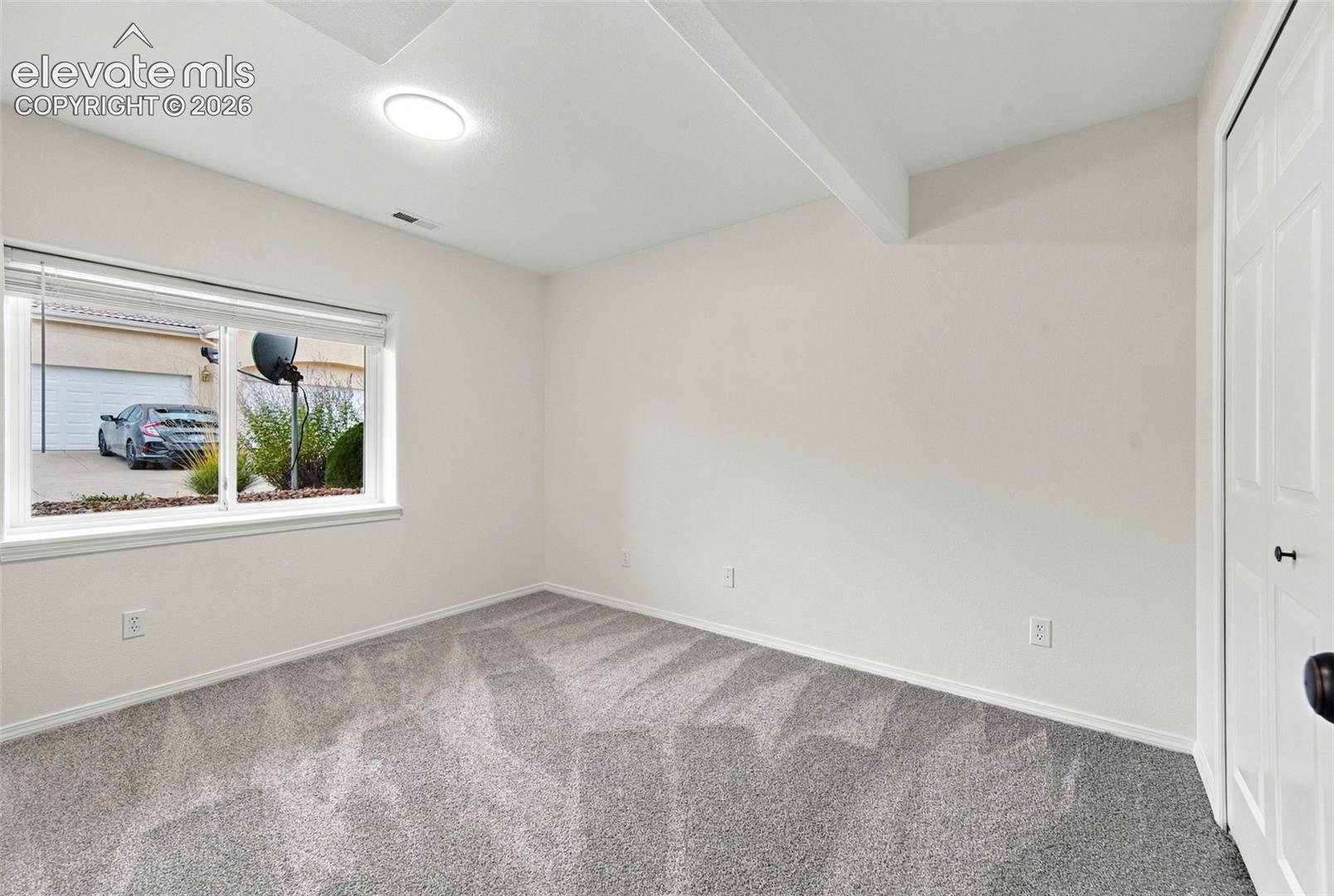 Neutral-toned room featuring neutral wall-to-wall carpeting, a large sliding window, a white interior door with a paneled design, and a recessed ceiling light