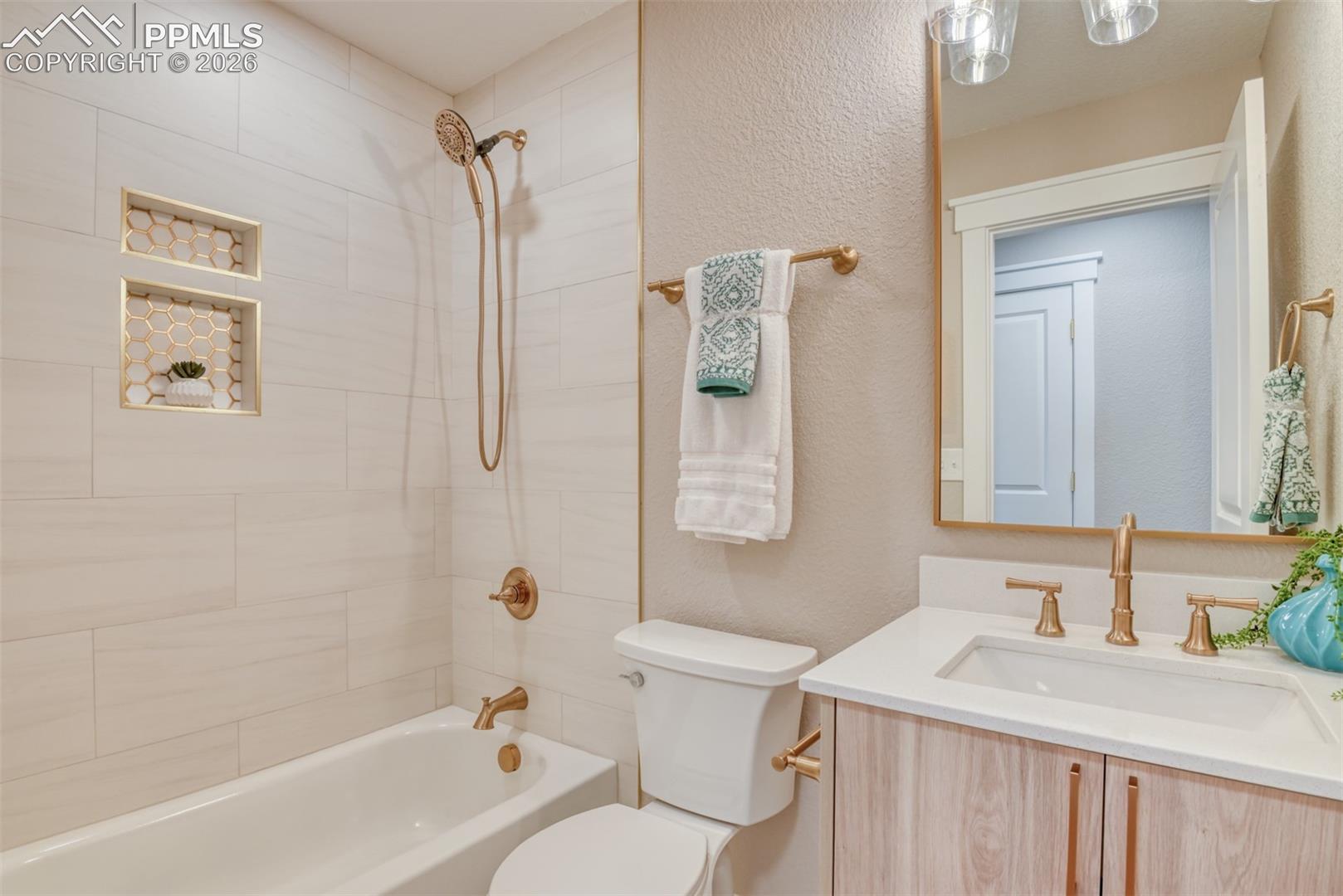 Bathroom featuring vanity, tub / shower combination, and a textured wall