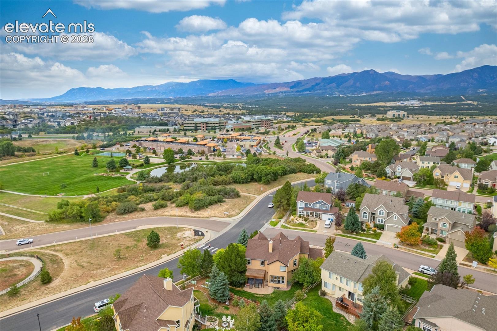 Expansive residential area with diverse architectural styles, surrounded by natural landscaping, and distant mountain ranges