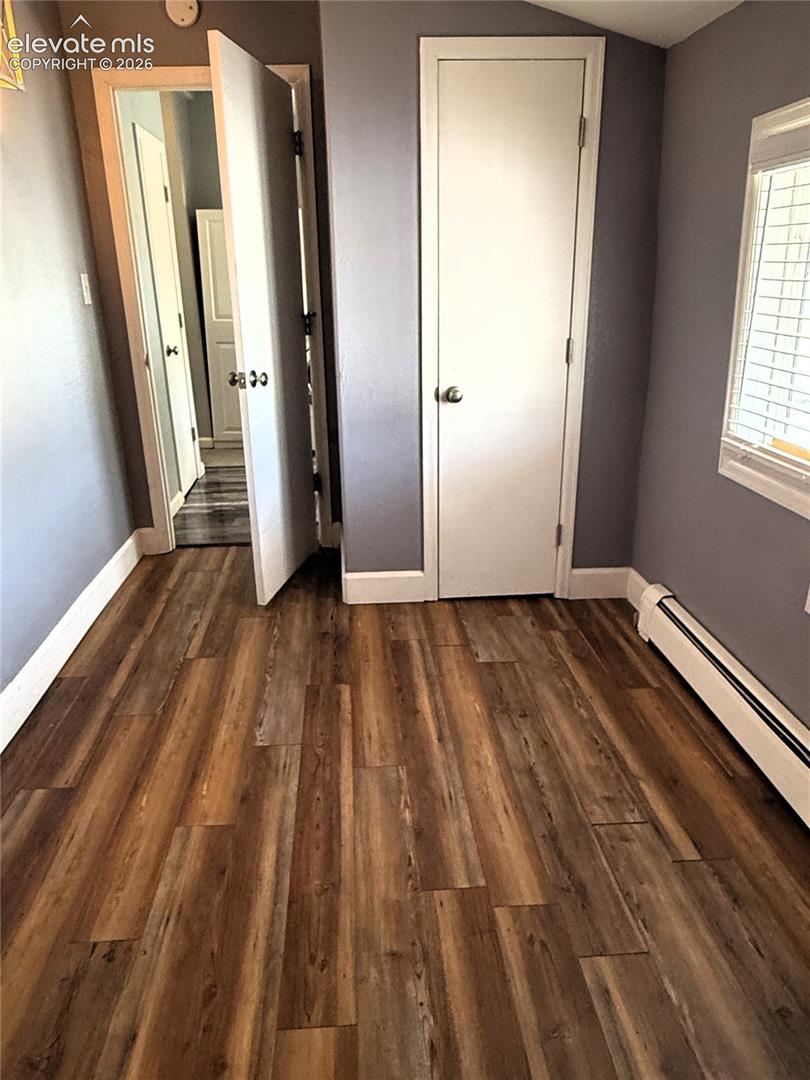 Wood-finish flooring, neutral wall paint, and interior doors with circular metal hardware