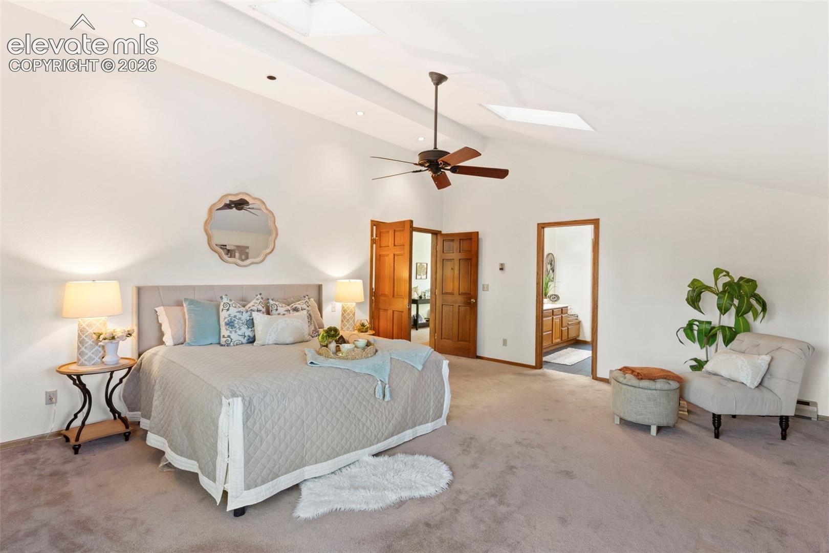 Vaulted ceilings featuring recessed lighting and integrated skylights, complemented by an overhead ceiling fan and six-panel wood doors