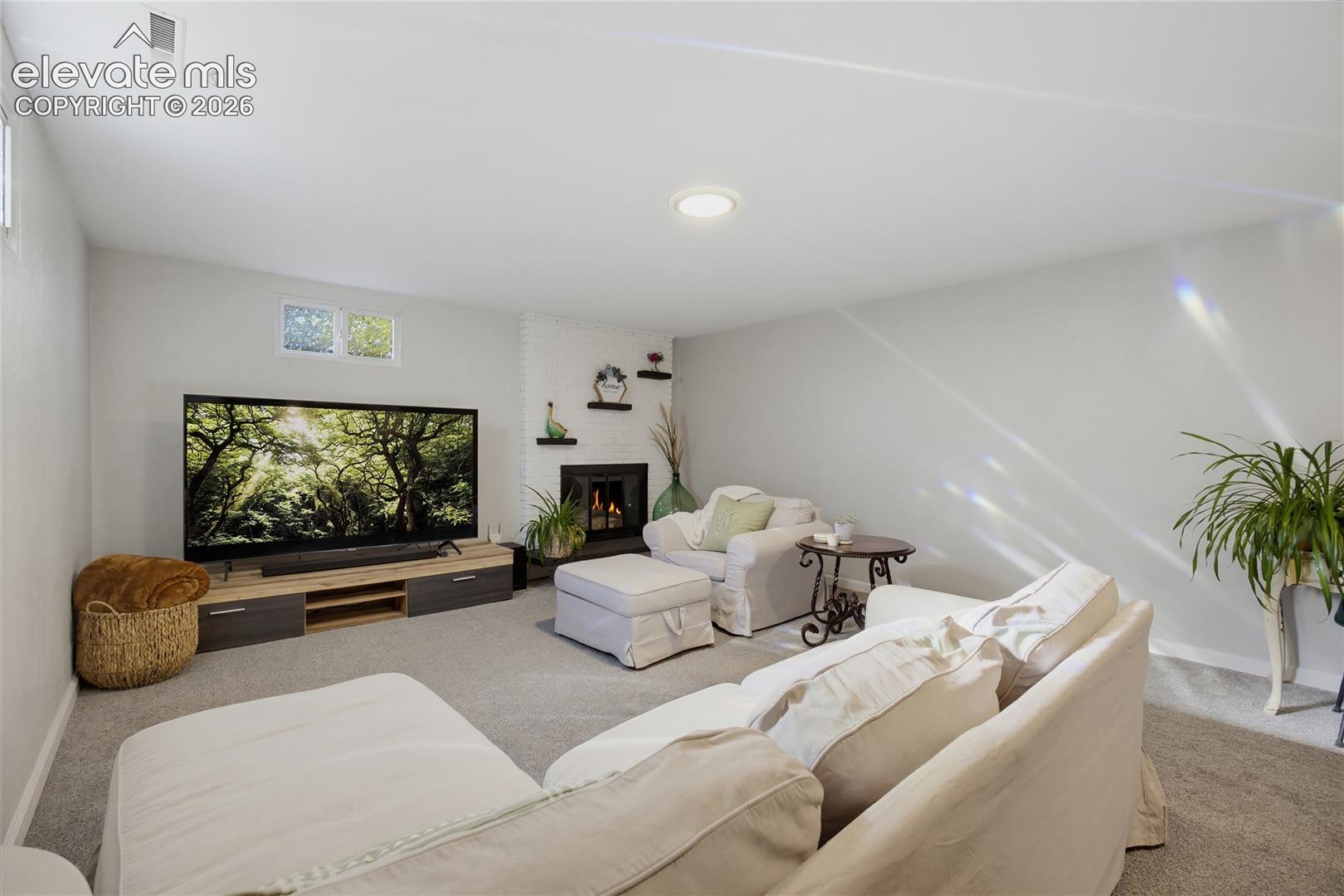 Recessed lighting, light gray carpeting, built-in fireplace, and a wood-finish media console