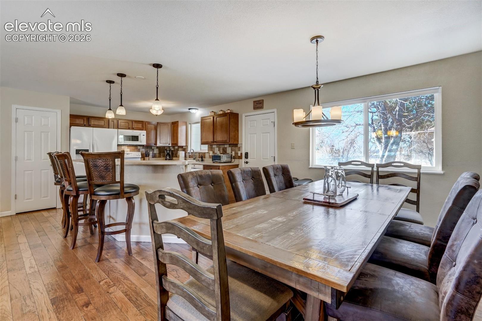 Wood-finish flooring, recessed lighting, white appliances, built-in cabinetry, and a large window