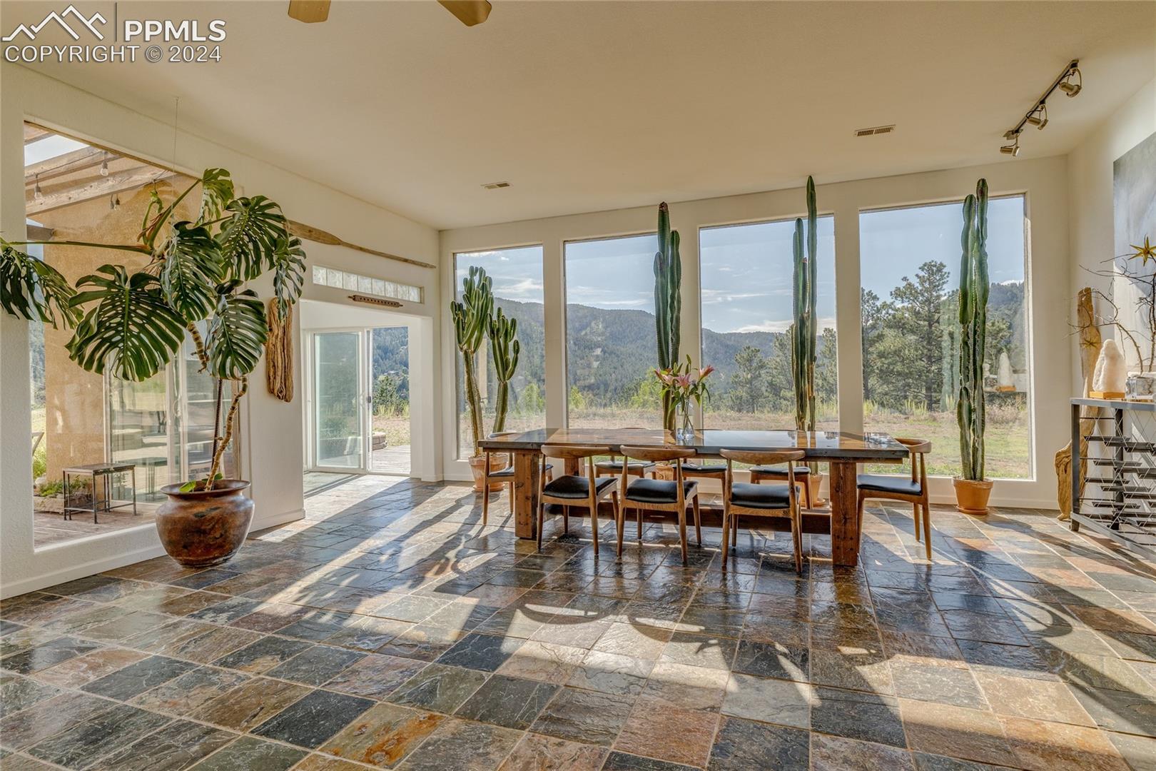 Sunroom / solarium featuring track lighting, a mountain view, ceiling fan, and a healthy amount of sunlight