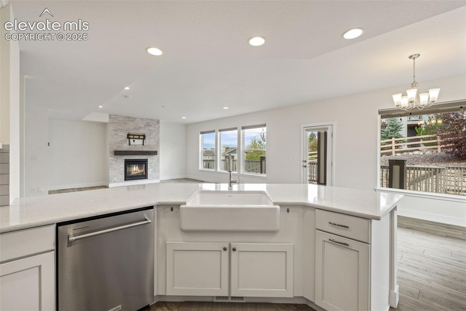 White kitchen island with a farmhouse sink, stainless steel dishwasher, and light-toned countertops