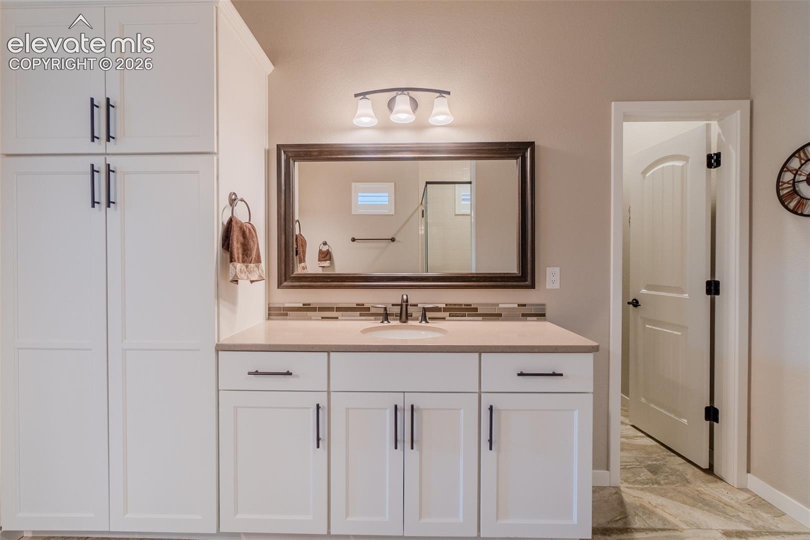 Bathroom featuring a single vanity with light-colored countertop, integrated sink, and dark-finish faucet