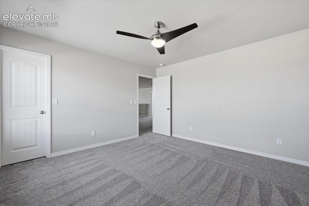 Neutral-toned interior space featuring wall-to-wall carpeting, three-panel interior doors, and a central ceiling fan with an integrated light fixture