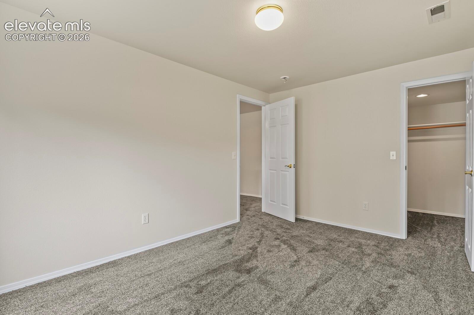 Neutral-toned interior featuring wall-to-wall carpeting, a flush-mount ceiling light fixture, and a built-in closet with shelving