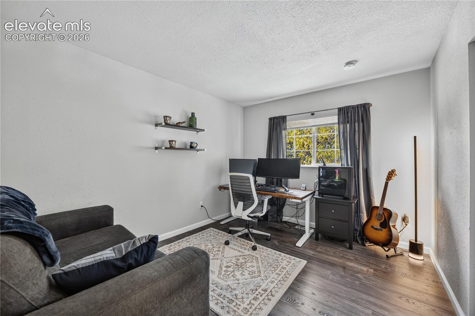 Room featuring wood-finish flooring, dual wall-mounted floating shelves, and a multi-pane window