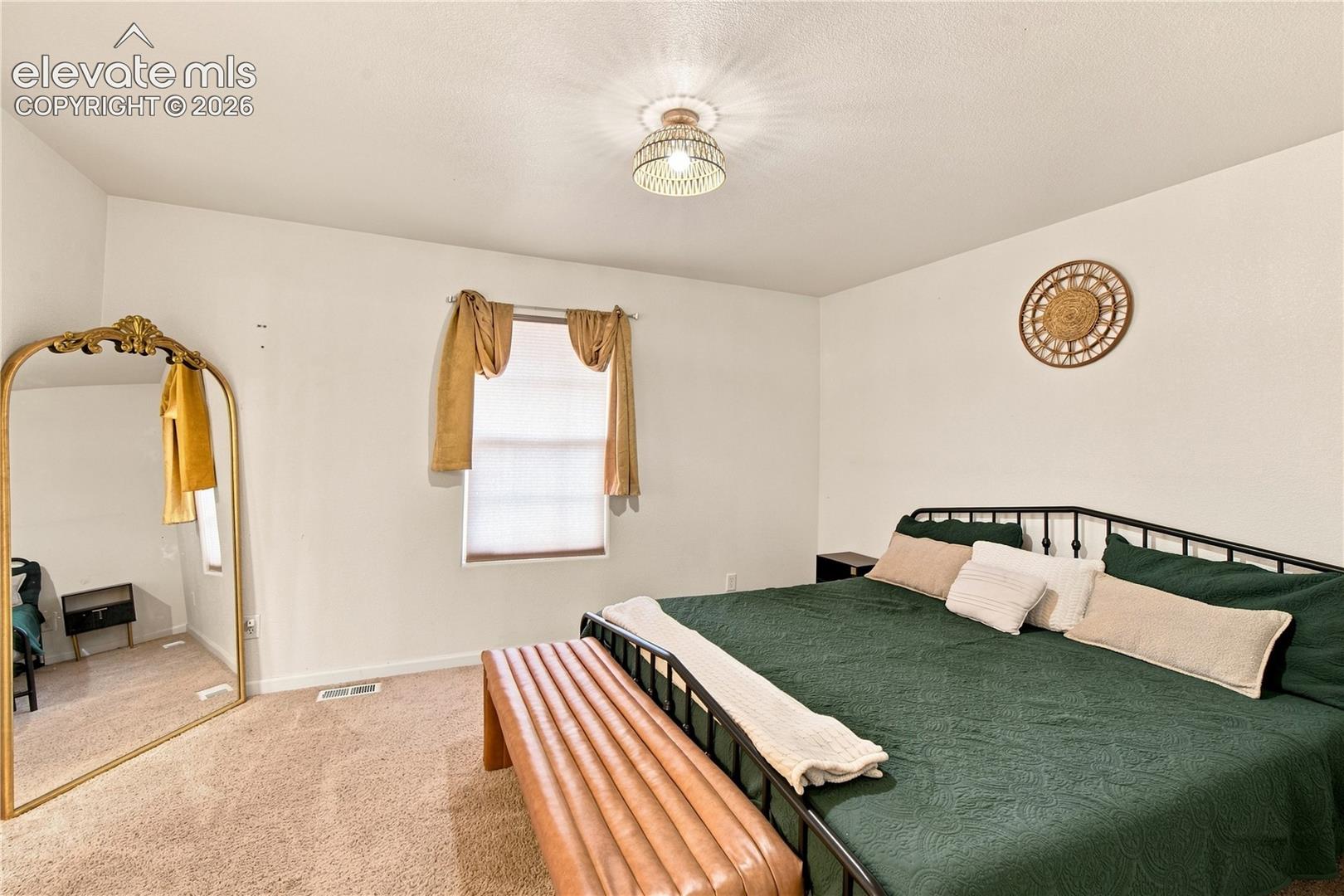 White painted walls, textured ceiling, a window with blinds, and carpeted flooring