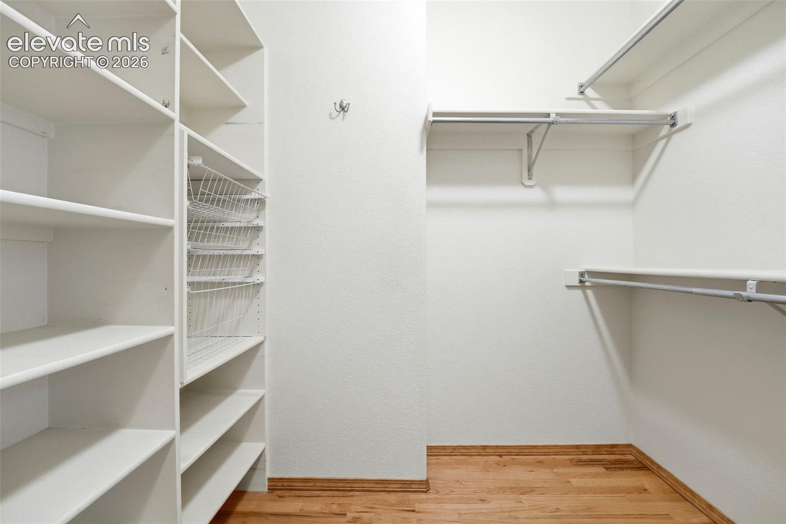 Walk-in closet featuring built-in shelving, wire baskets, and multiple hanging rods