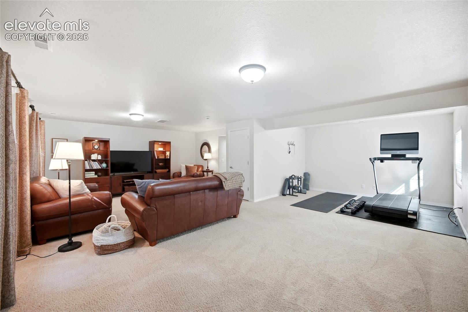 Recessed lighting illuminates this expansive carpeted room with distinct activity zones