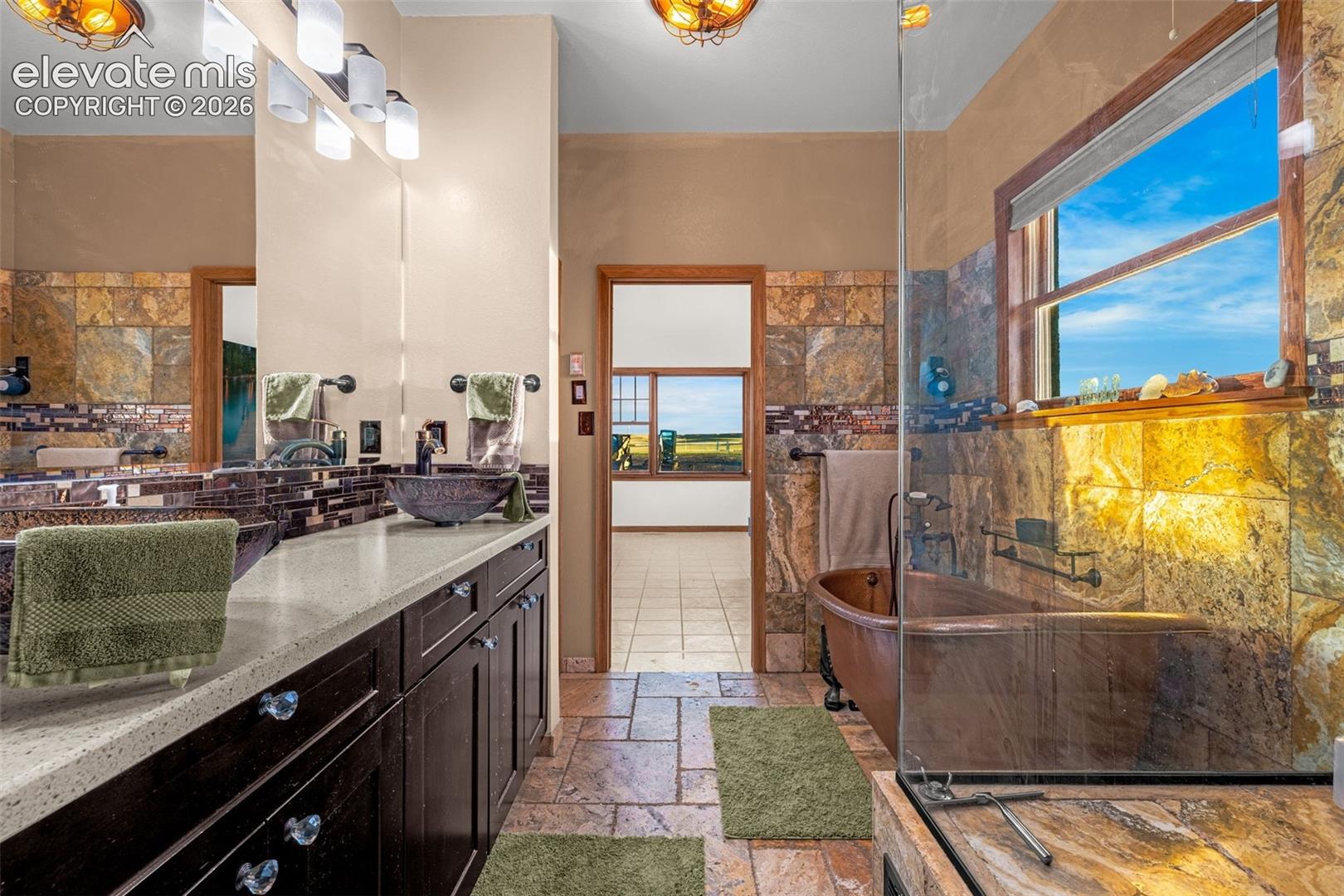 Dual vanity with vessel sinks, stone countertops, and dark wood cabinetry
