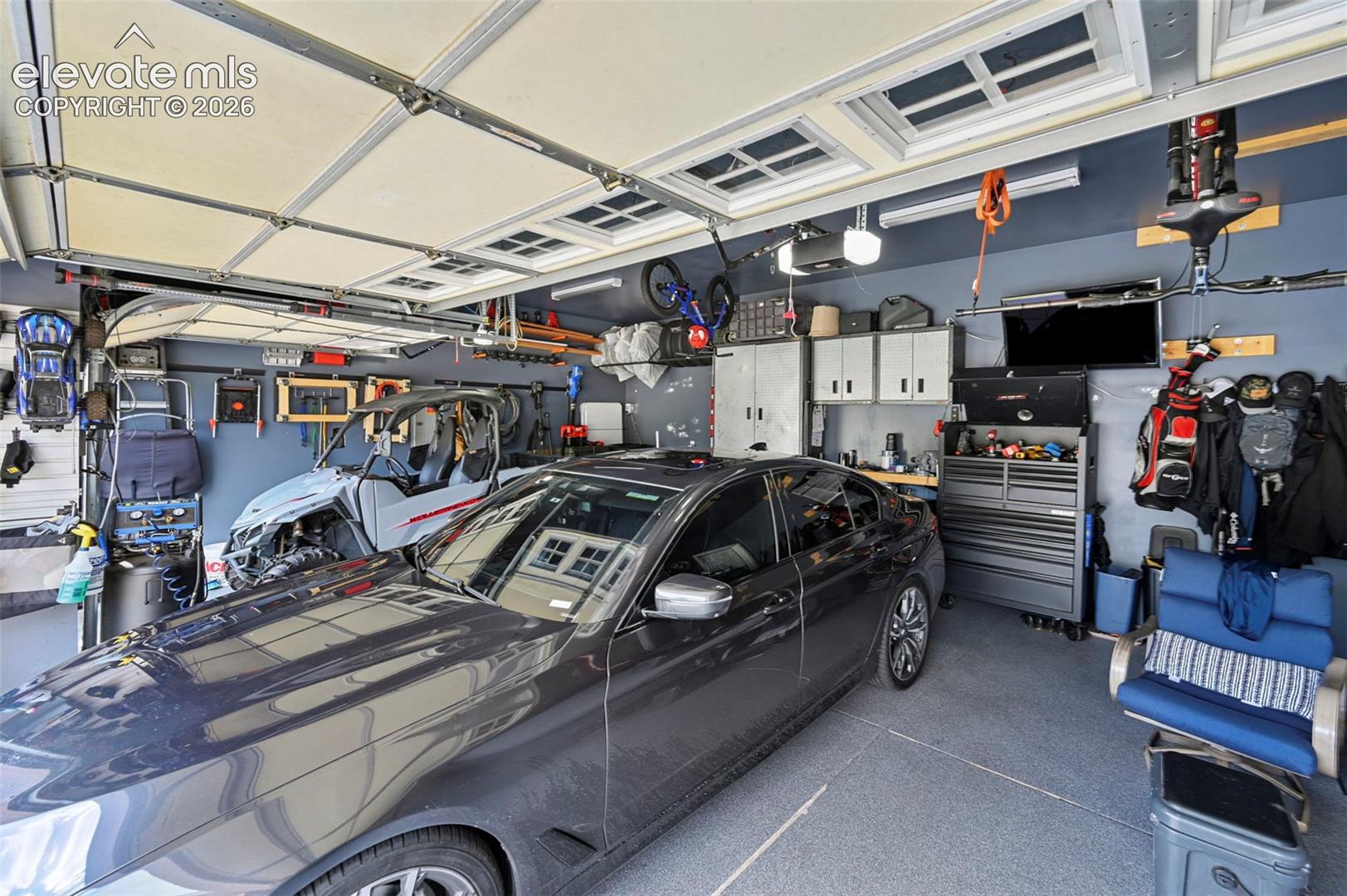 Attached garage with gray epoxy flooring, track lighting, and built-in white cabinetry
