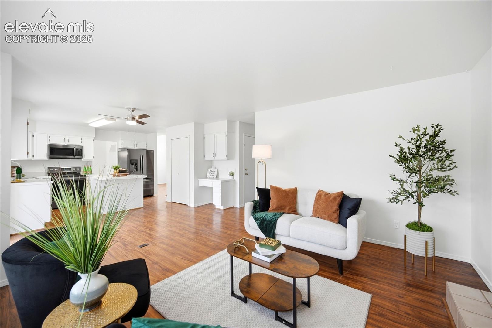 Open-concept floor plan featuring wood-finish flooring, white cabinetry, a center island, and a built-in workstation