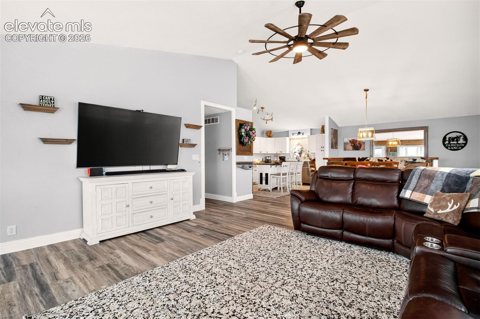 Bright living room featuring soaring vaulted ceilings, large windows, and a cozy woodburning stove!