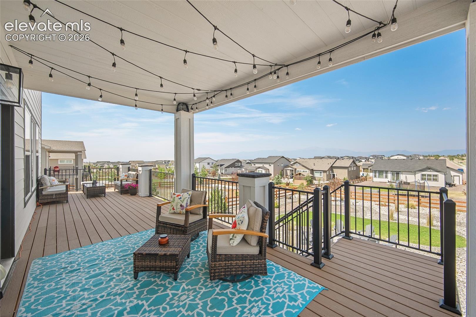 Spacious covered deck featuring composite decking, white ceiling with integrated lighting, and black metal railings