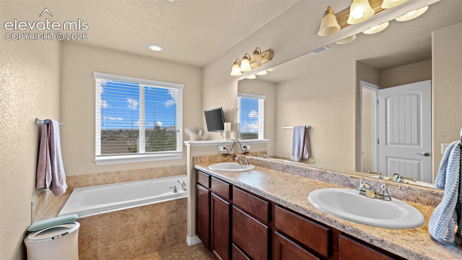 Bathroom featuring a dual vanity with undermount sinks and soaking tub