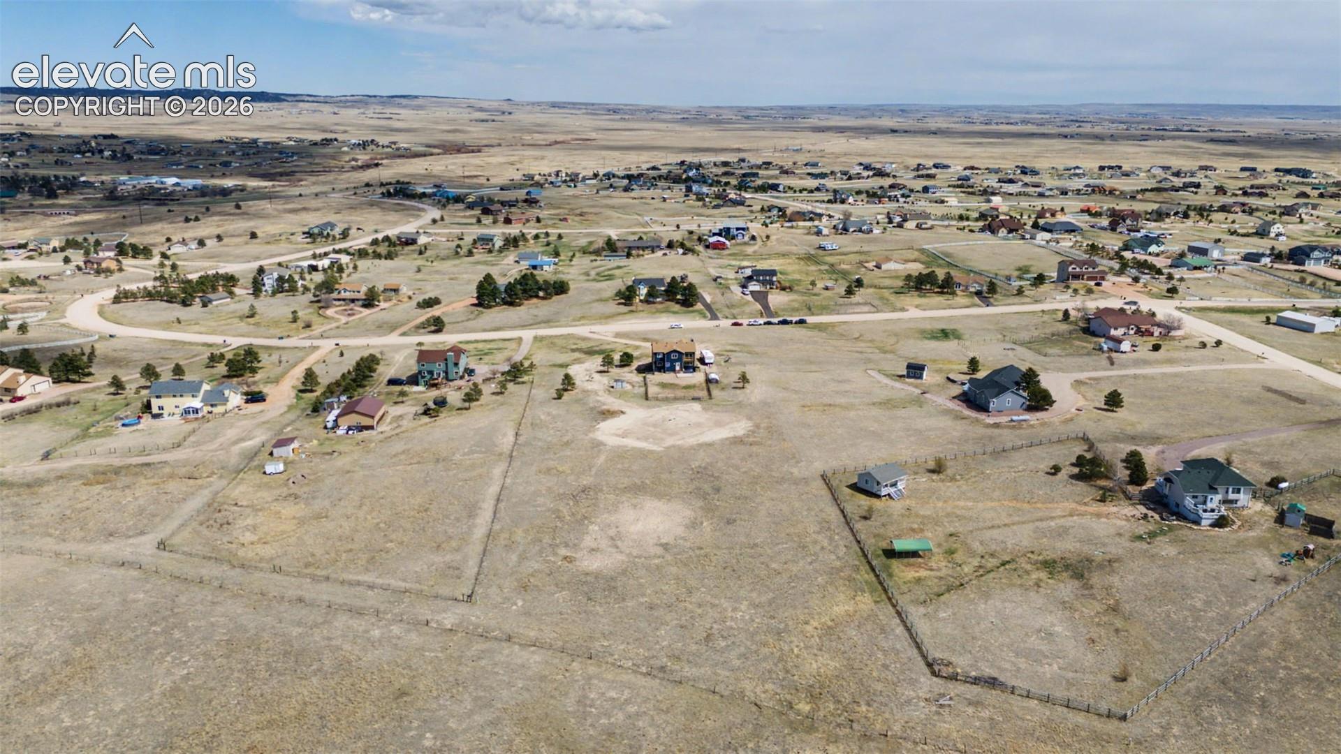 Aerial perspective of expansive acreage featuring native grass terrain, fenced boundaries, and horizon-wide topography