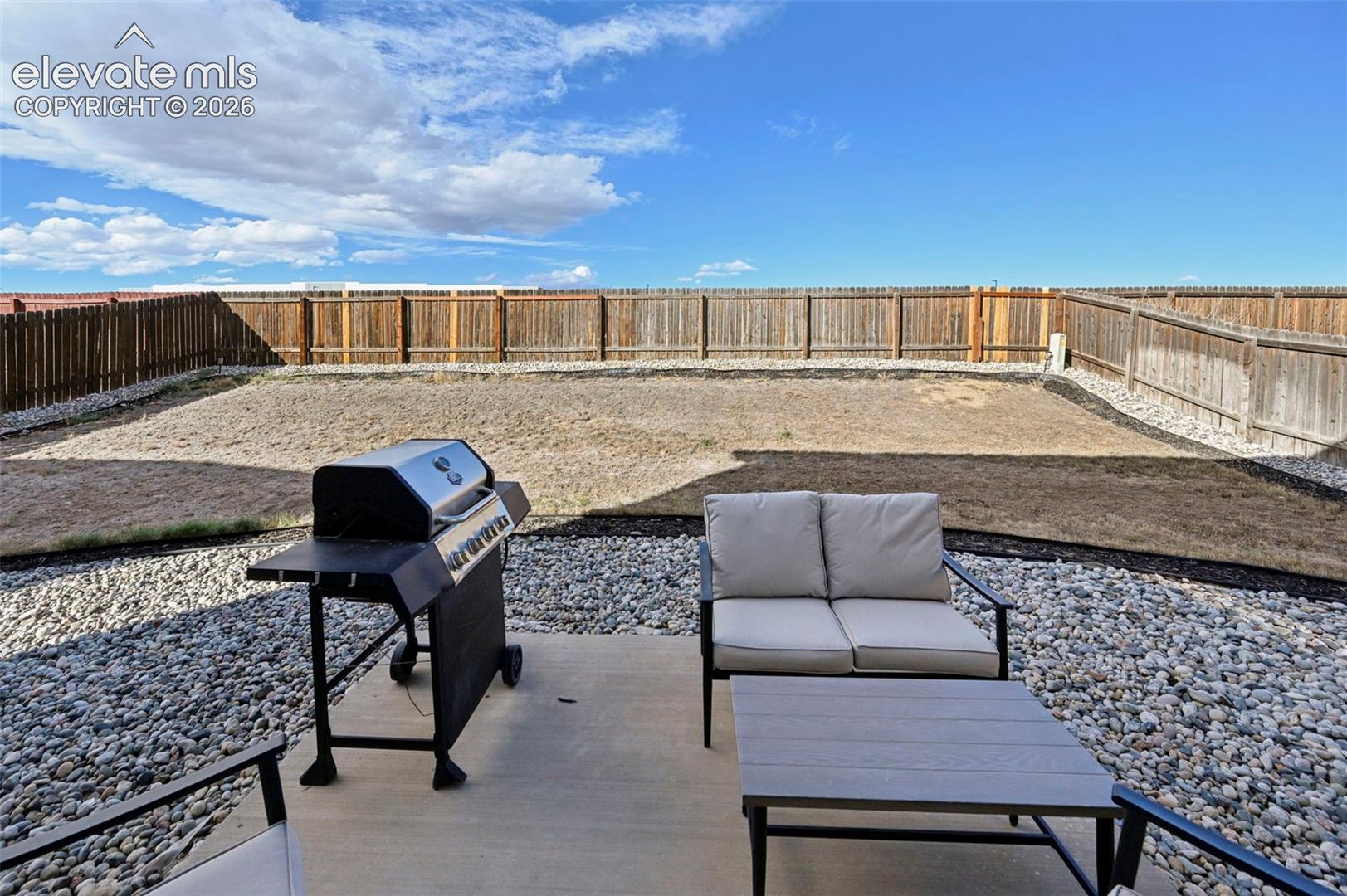 Concrete patio, stone ground cover, and wood privacy fencing