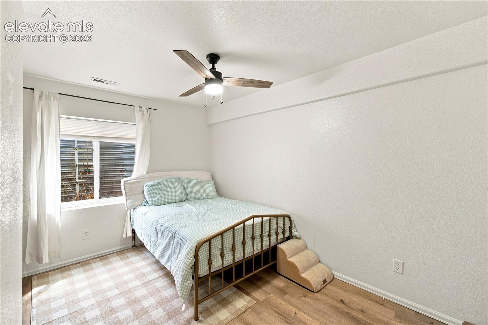 Recessed window with white trim, wood-finish flooring, and a ceiling fan with light fixture