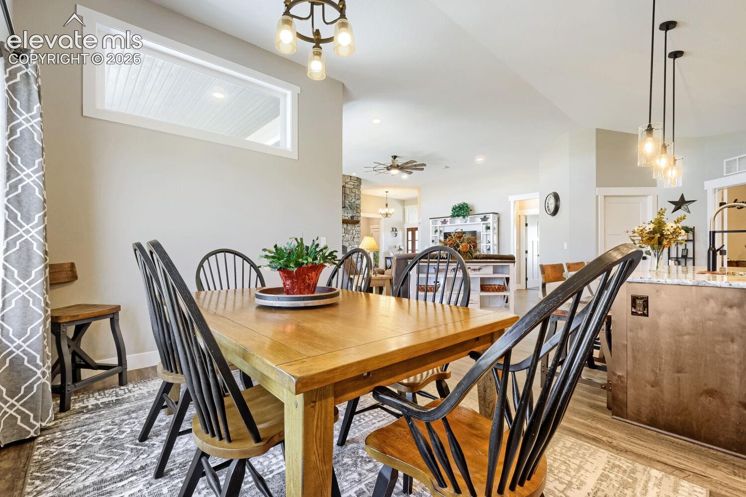 Recessed window with white trim, wood-finish flooring, vaulted ceiling, and pendant lighting