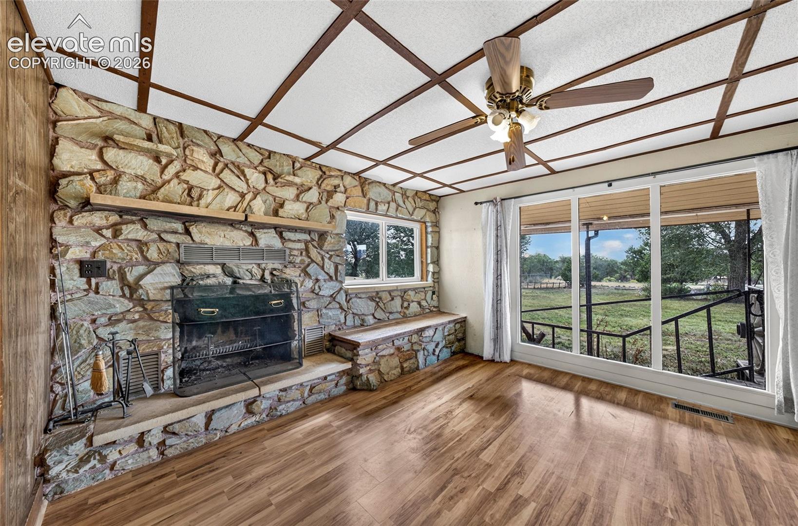 Stone-clad fireplace with hearth seating, and  ceiling fans