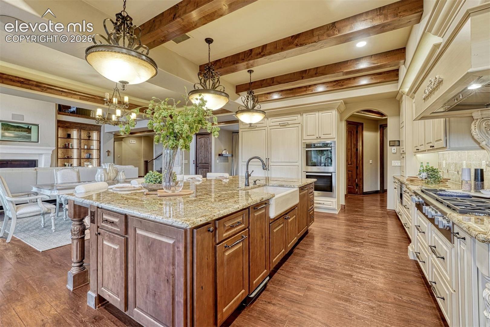 Kitchen island with granite countertop, farmhouse sink, and wood-finish flooring