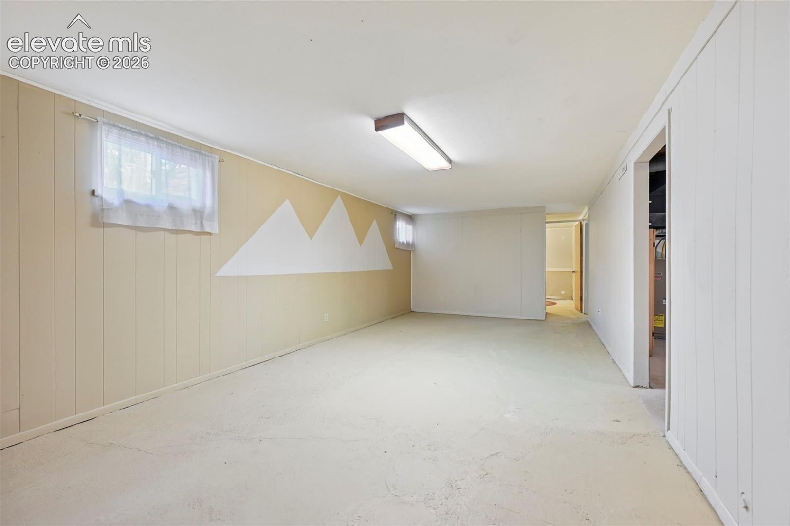 Finished basement room featuring painted concrete flooring and paneled walls