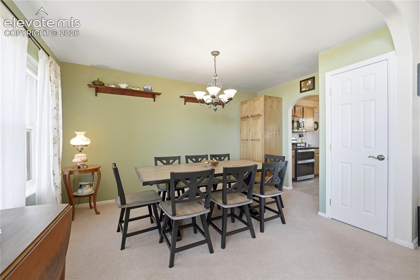 Recessed window, arched entryway, overhead chandelier, built-in cabinetry, light-colored carpeting