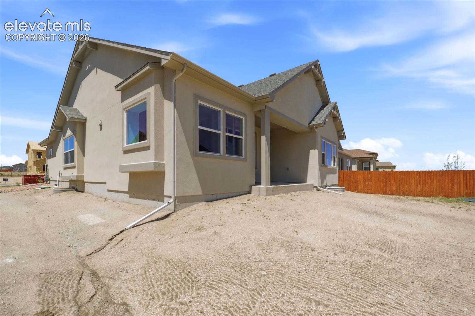 Stucco exterior residence featuring gabled rooflines, a covered porch, multi-pane windows, and a wood privacy fence