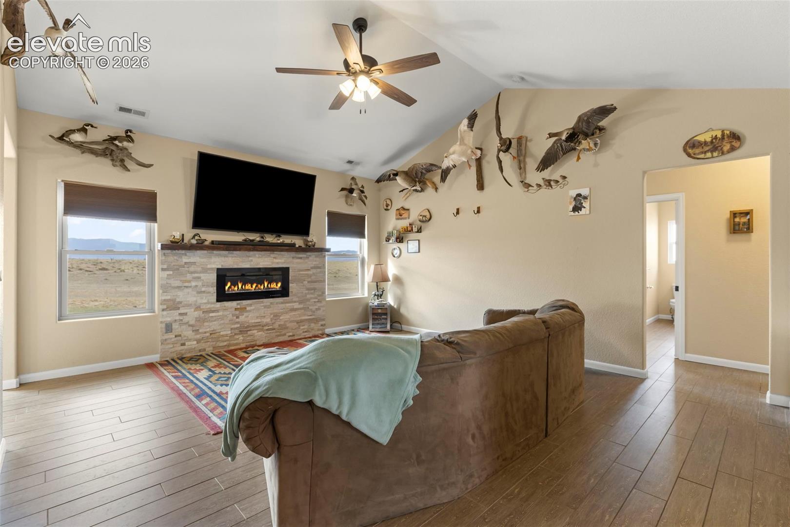 Vaulted ceilings, wood-finish flooring, and a floor-to-ceiling stone-veneer fireplace with an integrated linear firebox