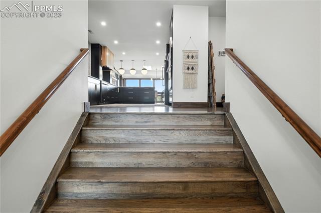 Stairs with hardwood / wood-style floors and recessed lighting