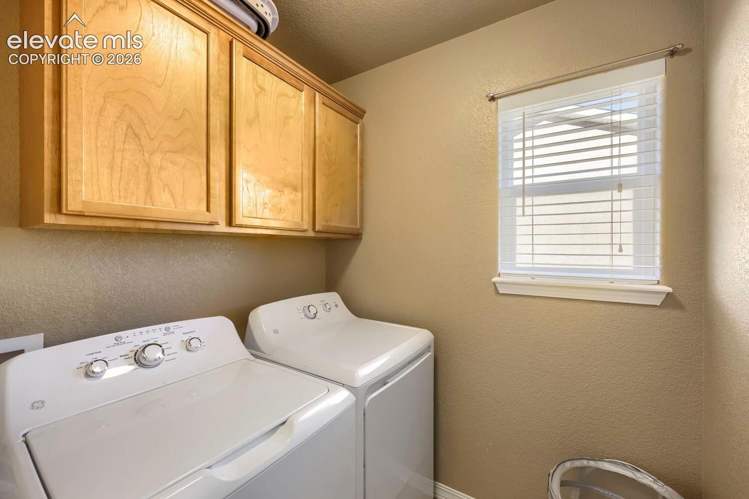Built-in natural finish wood cabinetry, window with horizontal blinds, and neutral wall tones