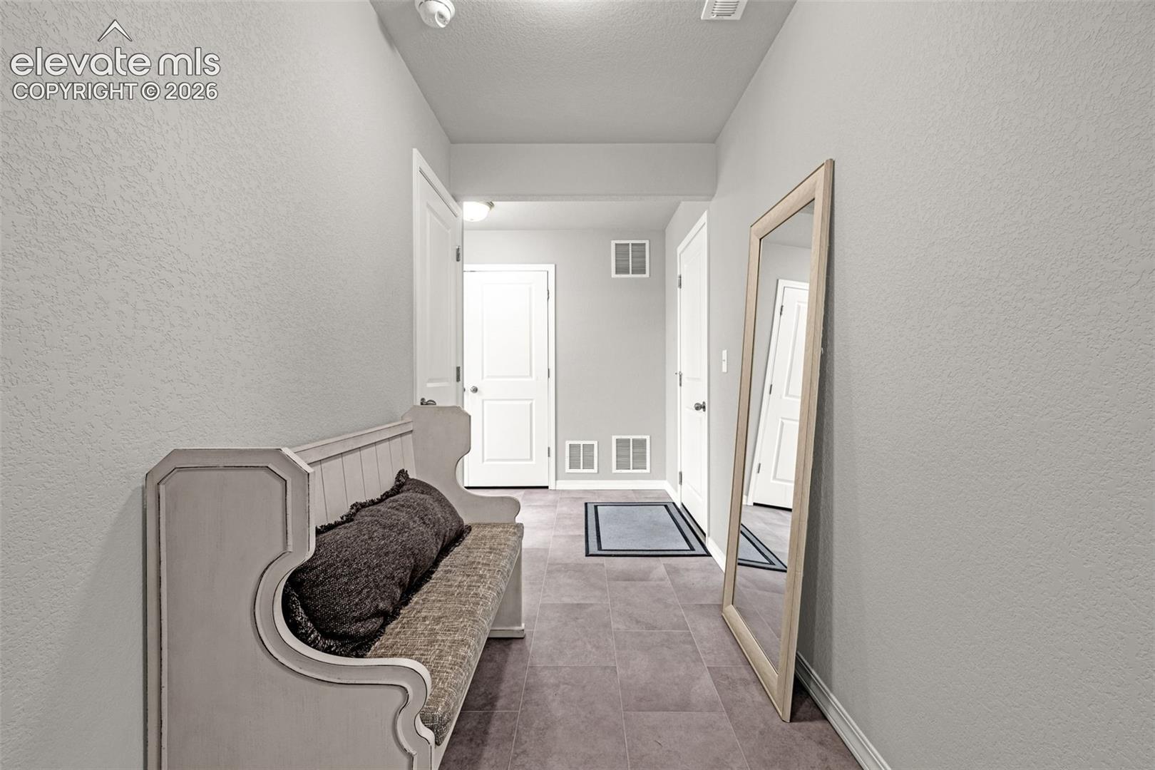 Entryway featuring tiled flooring, light gray walls, white baseboards, and multiple white paneled doors