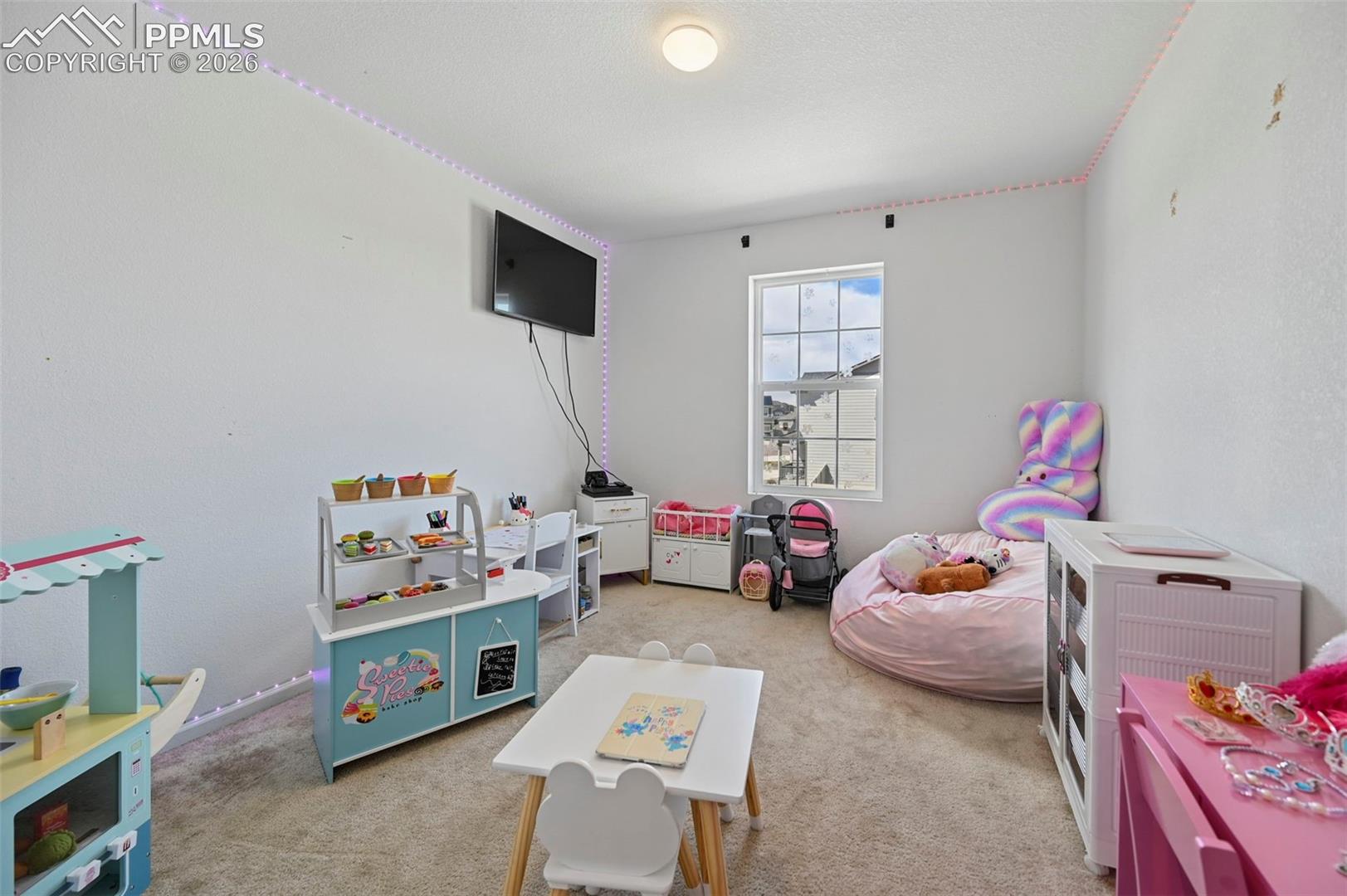 Room featuring a single pane window, mounted television, recessed ceiling light, and wall-to-wall carpeting