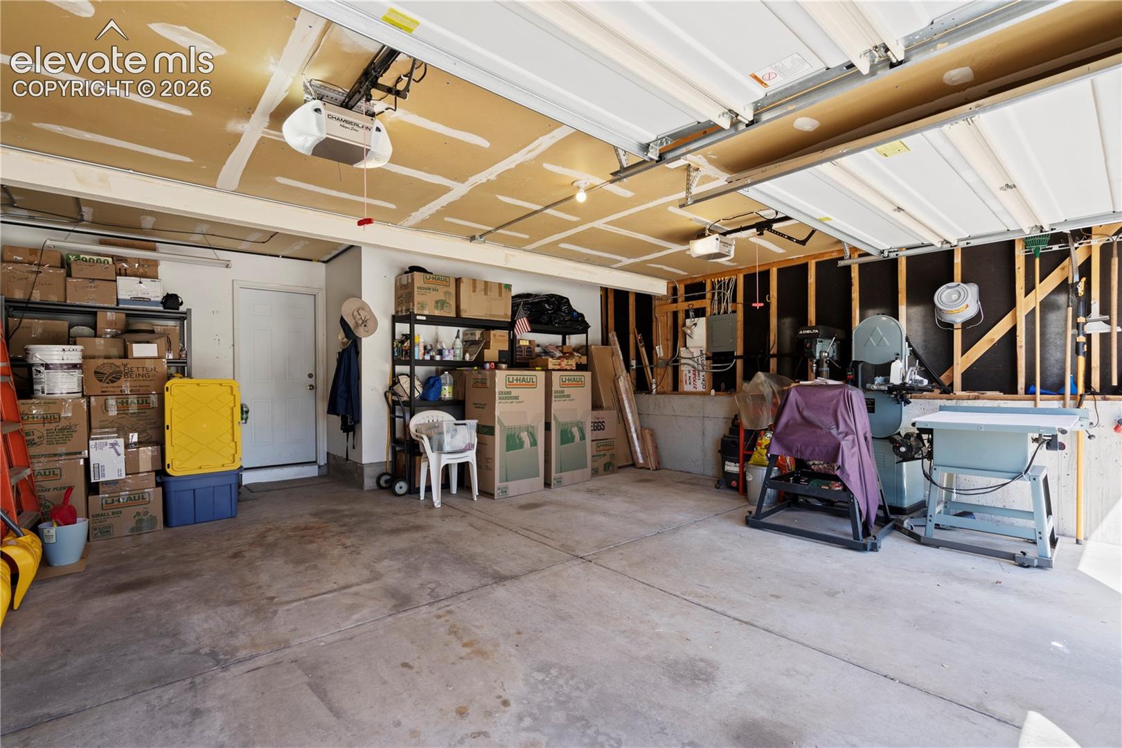 Concrete flooring with exposed ceiling joists and two overhead garage door openers
