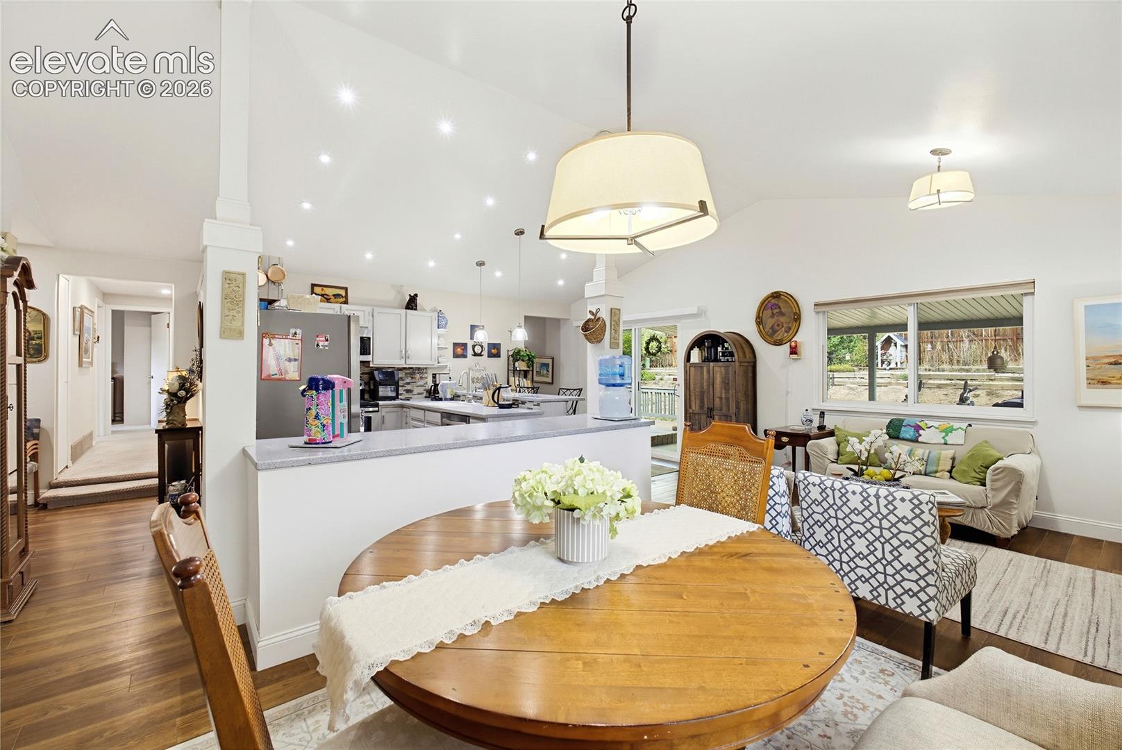 Vaulted white ceiling with recessed lighting, wood-finish flooring, white kitchen cabinetry, and light gray countertop