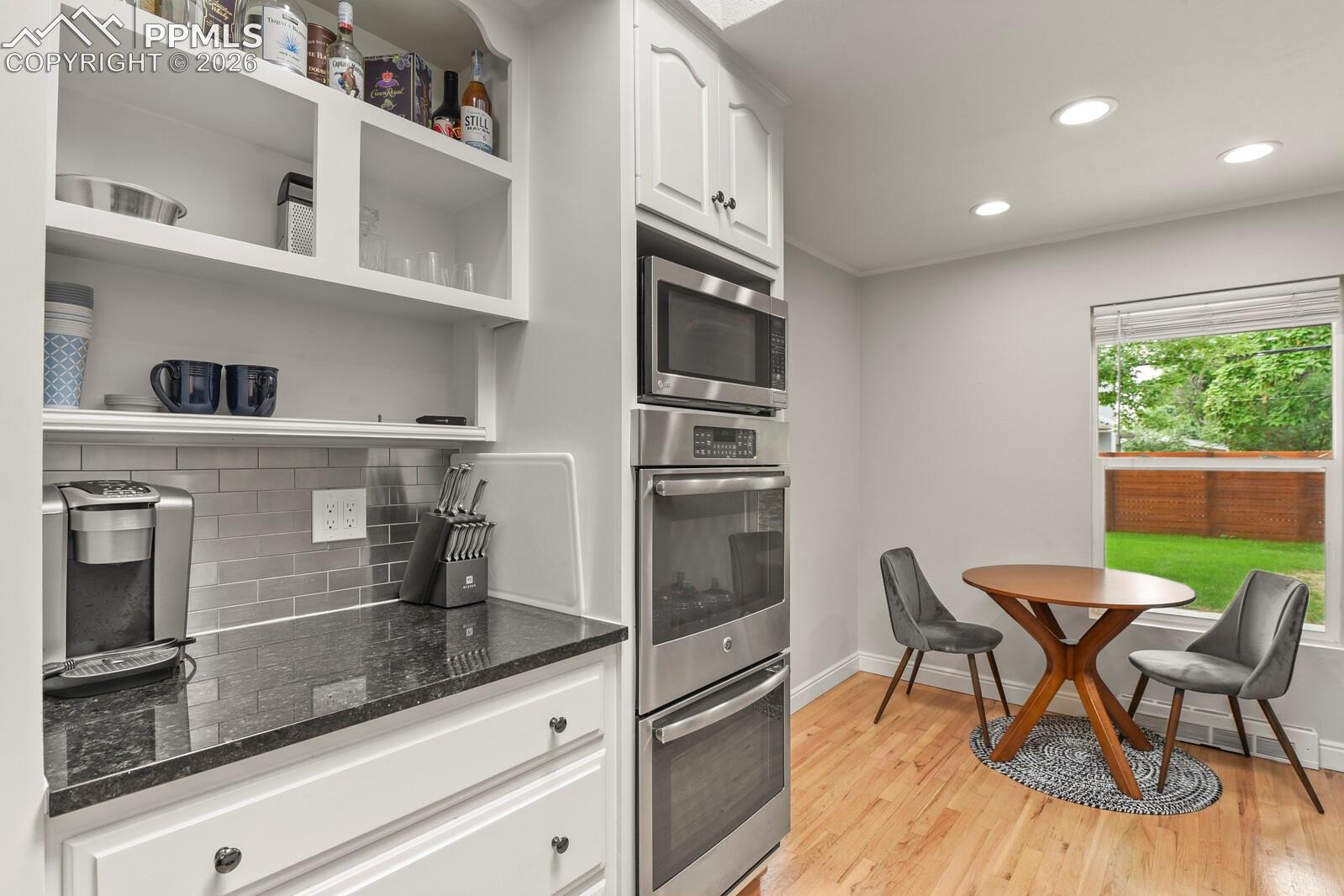 Contemporary kitchen featuring stainless steel built-in double oven, white cabinetry and a subway tile backsplash