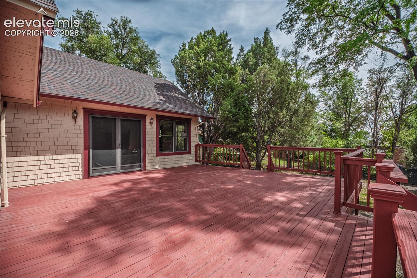 Expansive wood deck with a red finish, featuring a matching wood railing and integrated steps
