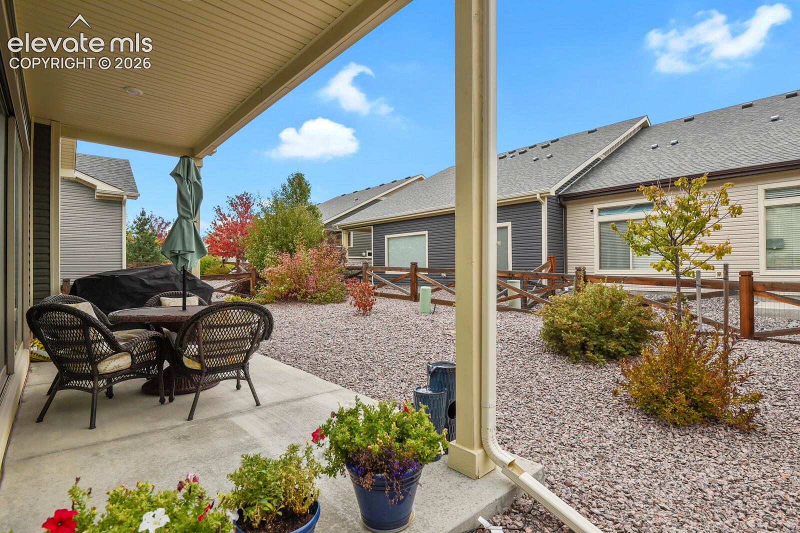 18'X9' Covered patio featuring an Xeriscaped yard and low maintenance landscaping and wood-post fencing